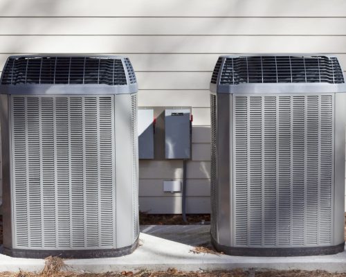 Two,Side-by-side,Heat,Pumps,On,Concrete,Slab,Against,House,Wall. Two,Side-by-side,Heat,Pumps,On,Concrete,Slab,Against,House,Wall.